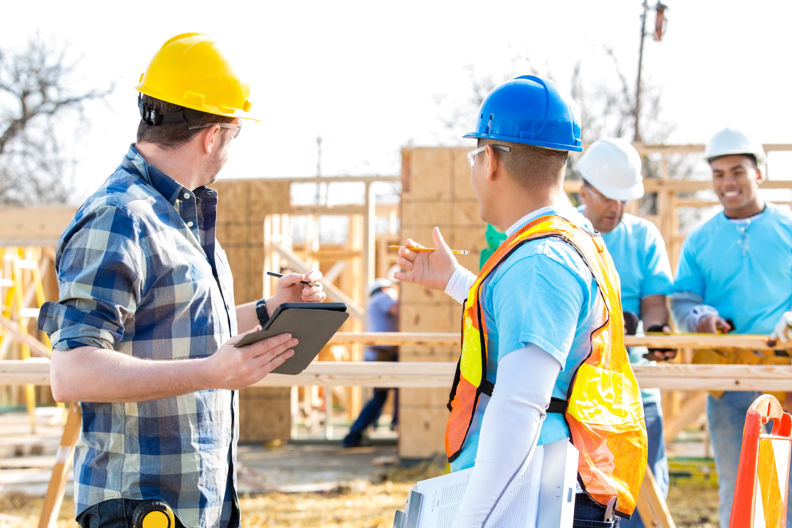 Workers talking to a inspector at a new home construction job site.