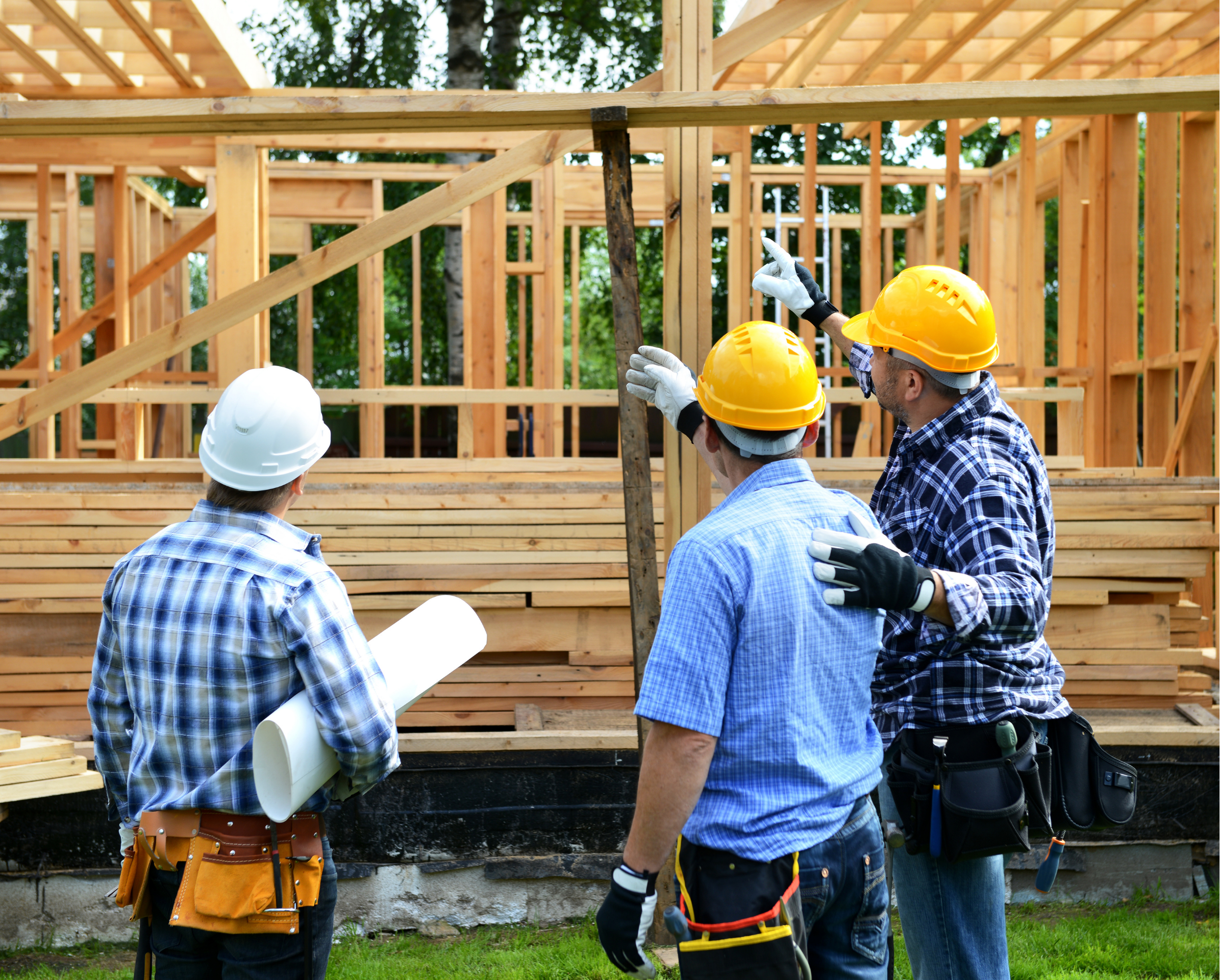Workers discussing the framework of a new home being built.