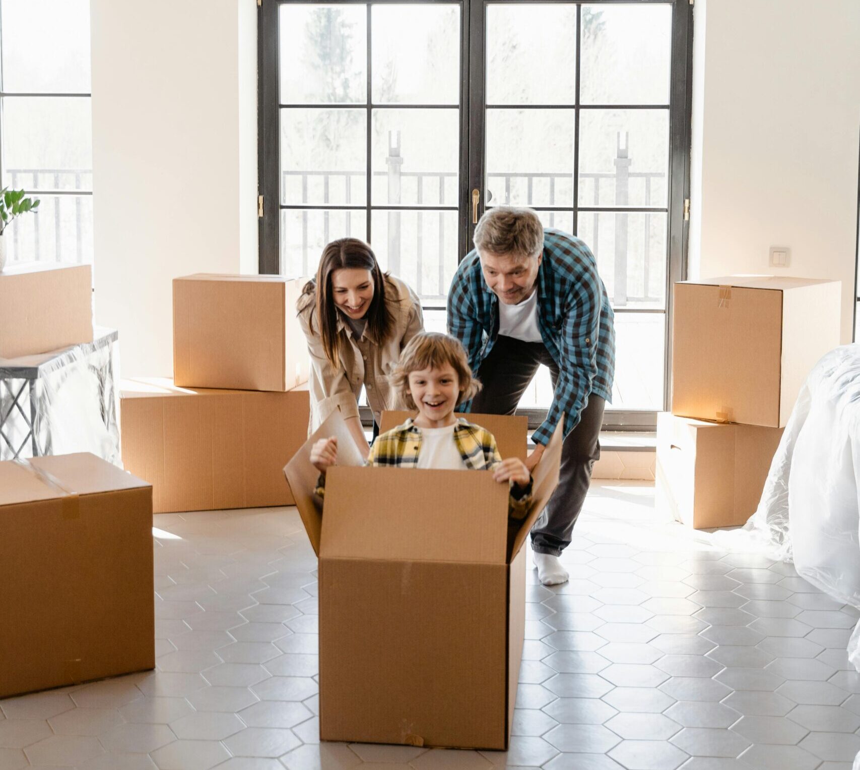 Family playing with moving boxes at home, creating happy moments indoors.
